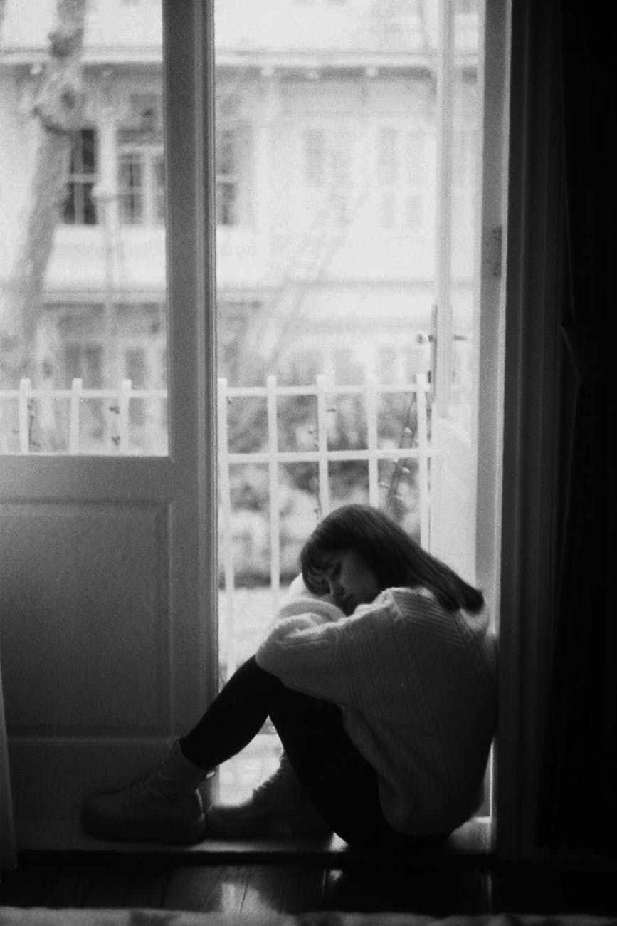 sad woman sitting in doorway of balcony
